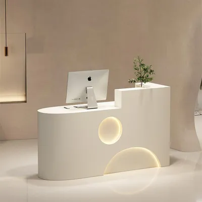 A modern reception desk with a computer and a small plant.