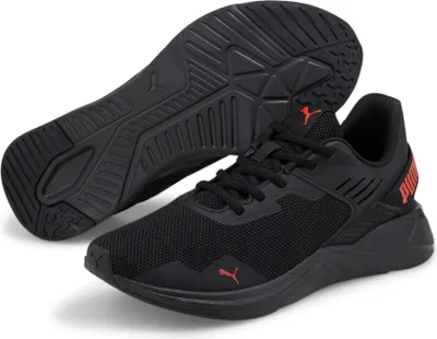 A pair of black Puma trainers with orange accents, shown from a slightly elevated side angle with the sole of one shoe visible.
