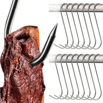A close-up of a meat hook piercing a piece of meat, with a row of S-hooks in the background.