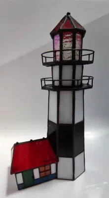 Tiffany-Leuchtturm mit kleinen Haus. Leuchtturm ist schwarz-weiß gestreift und hat ein rotes Dach.