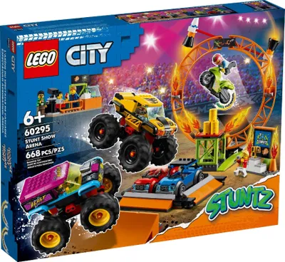 The image shows the packaging of a LEGO City Stuntshow Arena playset, featuring monster trucks, toy cars, and a motorcycle performing stunts in an arena setting.