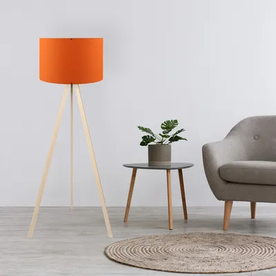 A floor lamp, a side table with a plant, and an armchair are arranged in a room.