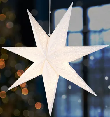 A white, 3D star-shaped paper lantern with small lights, hanging indoors.