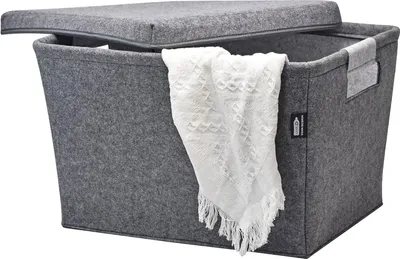 A grey felt storage basket with a lid and a white blanket draped over the side, set against a white background.