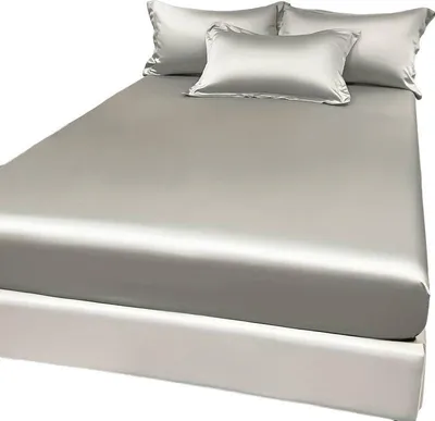 Helles graues Satin-Bettwäscheset auf einem weißen Bettrahmen, mit zwei Standardkissen und einem kleineren Kissen