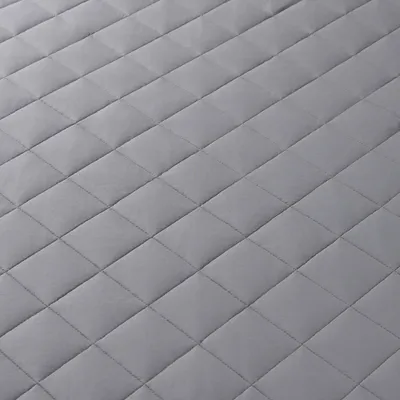 A close-up, angled view of a quilted gray blanket.