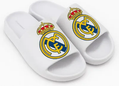 A pair of white Real Madrid slides with the team's crest on each.