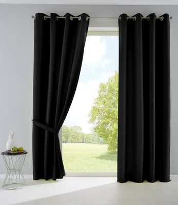 Black curtains are shown hanging in front of a window with a view of trees and a grassy field.