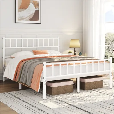A white metal bed frame with a headboard and footboard, dressed with bedding and blankets, in a bedroom setting.