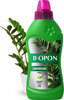 A bottle of plant fertilizer next to a potted plant.