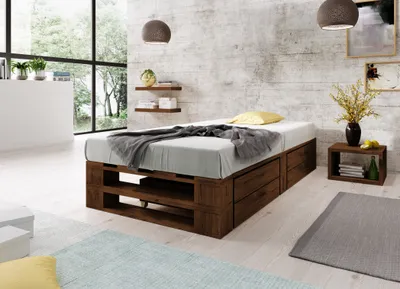A bedroom scene with a wooden pallet bed frame, bedding, and bedside table.