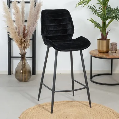 A black bar stool is shown in a room with decorative plants and a ladder.