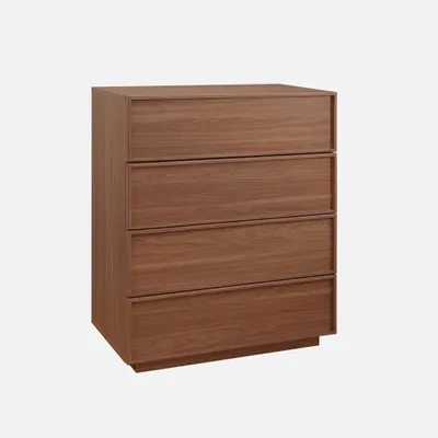 A wooden chest of drawers with four drawers against a plain background.