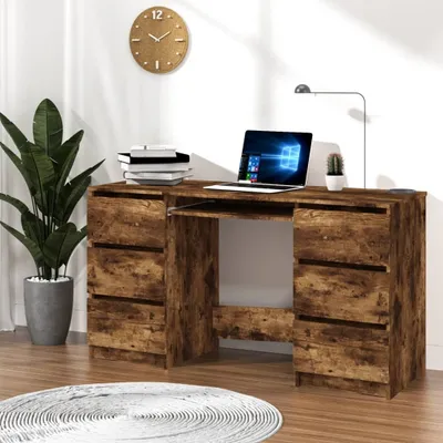 A wooden desk with drawers and a laptop on top, a plant to the left, and a clock on the wall.