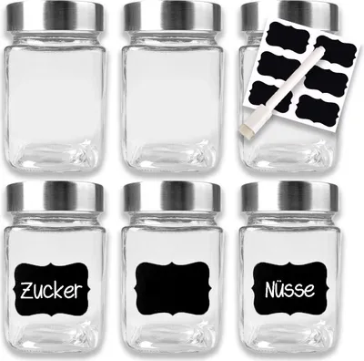 Six clear glass jars with silver lids are arranged in two rows of three. Some jars have black labels with white text.