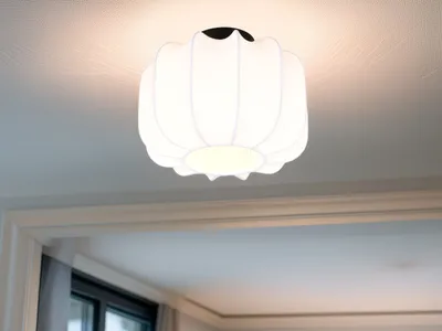 A white, fabric ceiling light fixture with a ruffled, pumpkin-like design is mounted on a white ceiling.