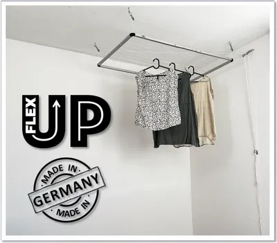 A ceiling-mounted clothes drying rack with clothes hanging on it, set against a white wall.