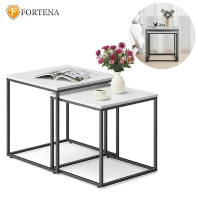 A set of two nesting square tables with white tops and black metal frames, displayed on a white background. A bouquet of pink and red flowers in a cream vase sits on the smaller table, and a cup and saucer are also present.
