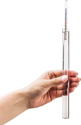 A hand holding a hydrometer.