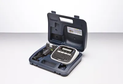 A Brother P-touch D200BWVP label maker is shown inside its carrying case, along with its power adapter and a starter tape cassette.
