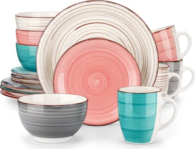 A collection of ceramic dishes and mugs in various colors and patterns, arranged in a studio setting.