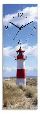 A lighthouse on a sandy dune under a blue sky with clouds.