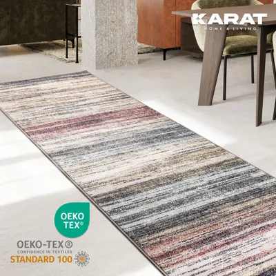 A runner rug with a striped pattern lies on a concrete floor next to a dining table and chairs.