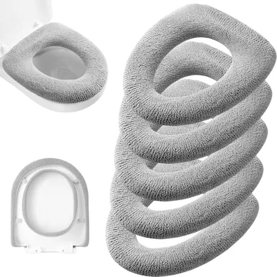 A set of five grey, fuzzy toilet seat covers are stacked on a white background, with one cover already installed on a toilet seat in the upper left corner, and another cover shown from the underside in the bottom left corner.