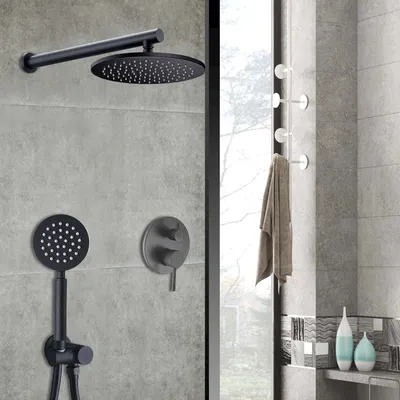 A black shower system mounted on a gray tiled wall, with a towel hanging on a rack to the right.