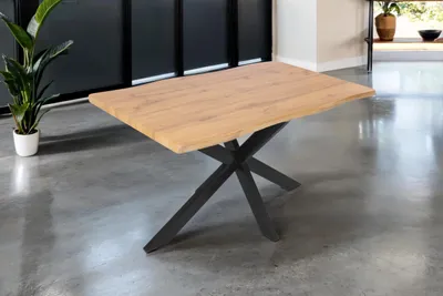 A wooden dining table with a black spider leg base is shown in a modern room setting.