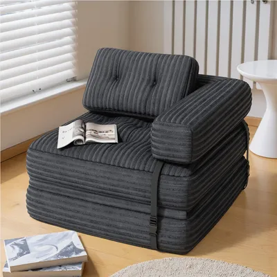 A dark gray foldable sofa bed is shown in a room with blinds and a white side table.