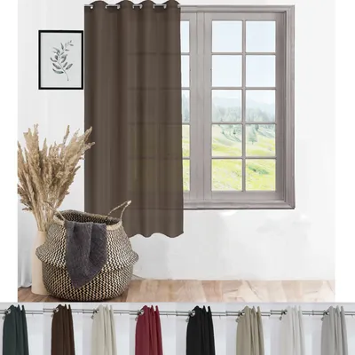 A dark brown sheer curtain hangs in front of a window, with a basket of blankets and dried reeds in the foreground.