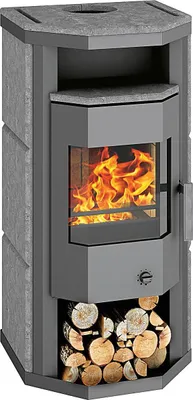 A freestanding wood-burning stove with a stone surround and a glass door showing flames. Logs are stored in the base.
