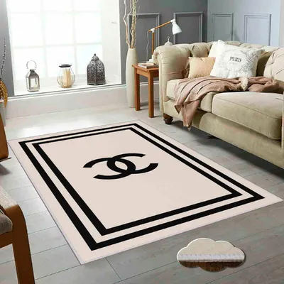 A beige rug with a black Chanel logo is placed in a living room setting.