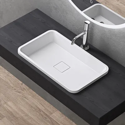 A white rectangular sink with a chrome faucet is placed on a dark wooden countertop.