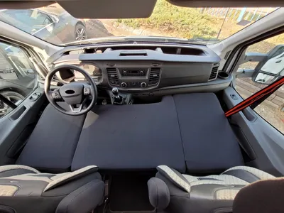 Interior view of a van with a custom bed installed over the front seats and dashboard.