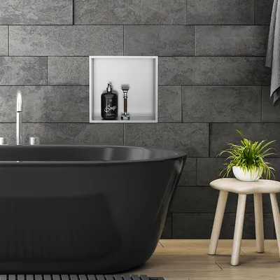 A black bathtub in a modern bathroom with stone tiles.