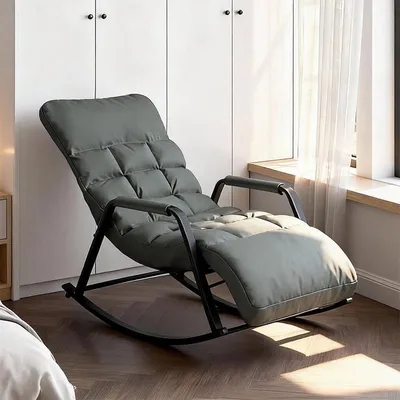 A gray rocking lounge chair is shown in a room with white cabinets and a window with sheer curtains.