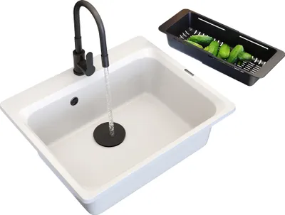A white kitchen sink with a black faucet and a black colander filled with cucumbers.