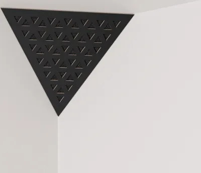A black triangular acoustic foam panel with a geometric pattern is mounted in the corner of a white room.