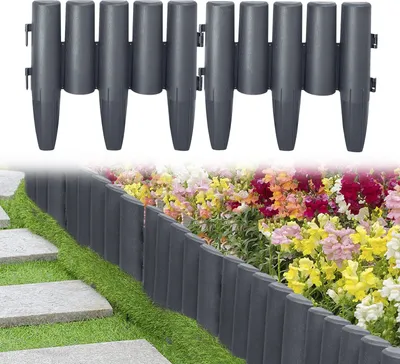 A garden border made of anthracite-colored plastic elements with a wood-like texture, installed along a flower bed and a stone pathway.