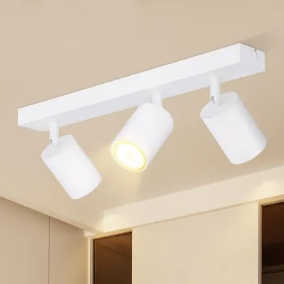 A white ceiling spotlight fixture with three adjustable lamps is mounted on a white bar attached to a light beige ceiling.
