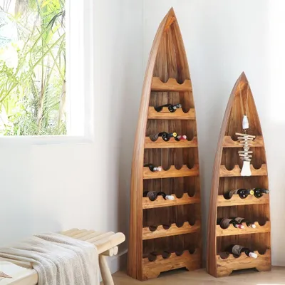 Two wooden wine racks shaped like canoes are displayed in a room with a window and a bench.