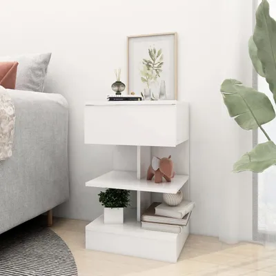 A white nightstand with a drawer and shelves next to a bed.