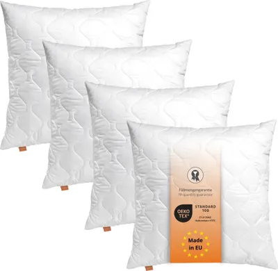 A set of four white pillows arranged diagonally on a white background.