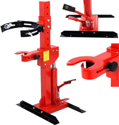 A red hydraulic spring compressor tool is shown against a white background. The tool is a mechanical device used to compress coil springs, typically for automotive suspension work. It features a sturdy base, a vertical support column with adjustable height