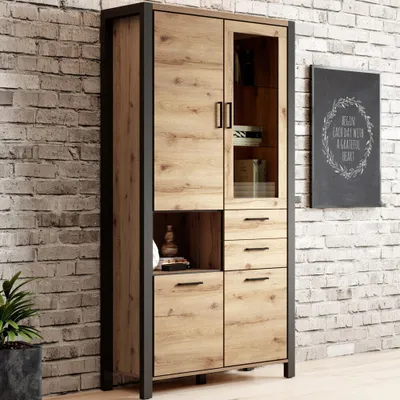 A tall cabinet with wooden doors and a glass-fronted section, set against a brick wall.