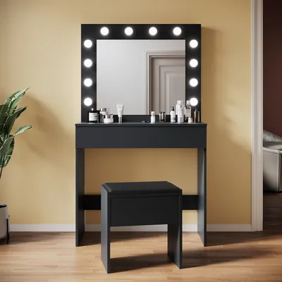 A black vanity table with a lighted mirror and a matching stool, set against a yellow wall.