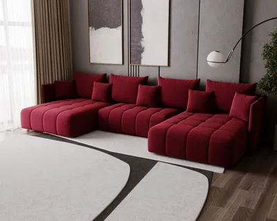 A modern living room with a large U-shaped red sofa, abstract art on the wall, and a floor lamp.
