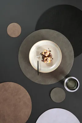 A flat lay of round placemats and coasters with a plate of dessert and a glass of drink.